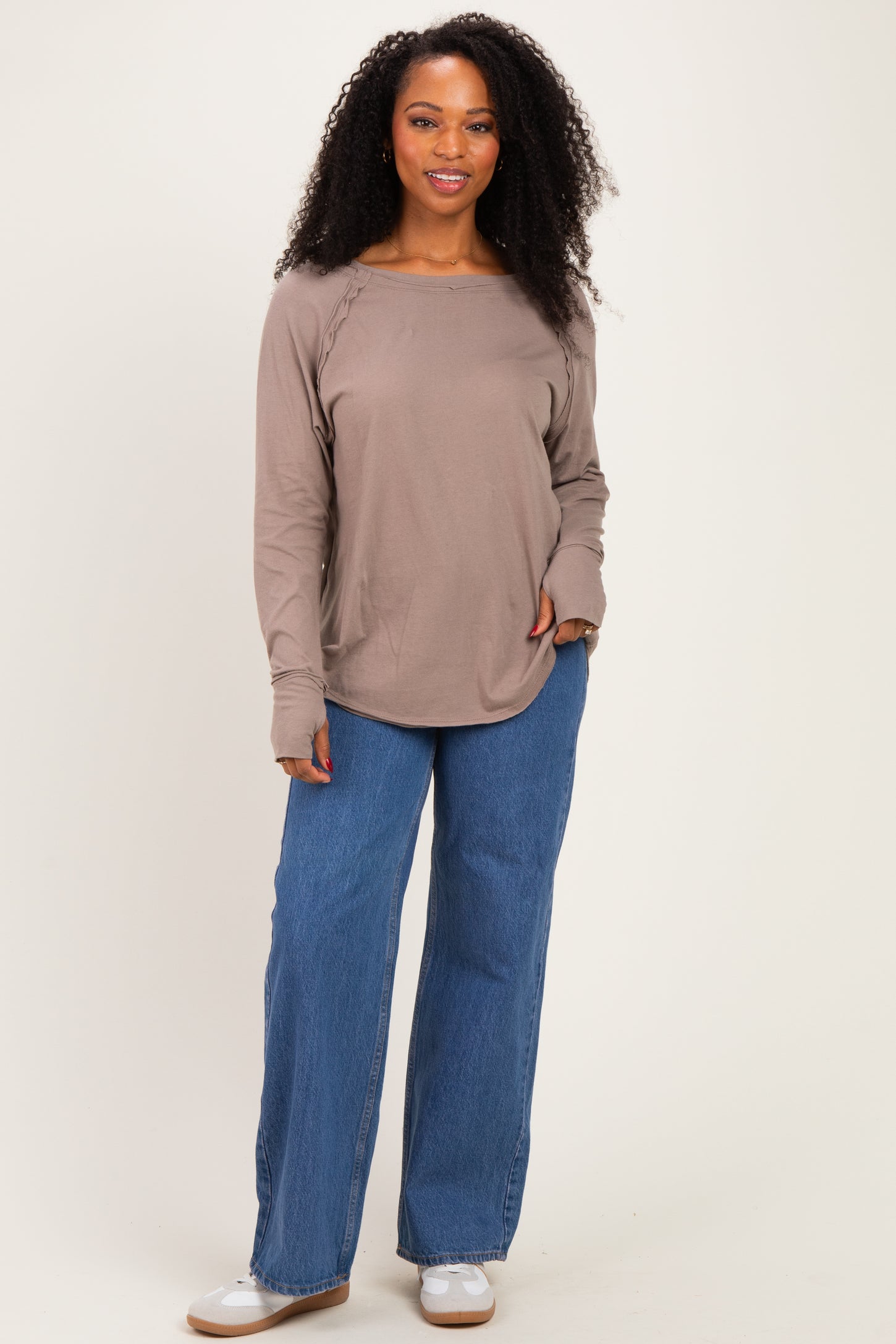 woman wearing a taupe long sleeve top with side ruching and high-waisted blue wide-leg jeans