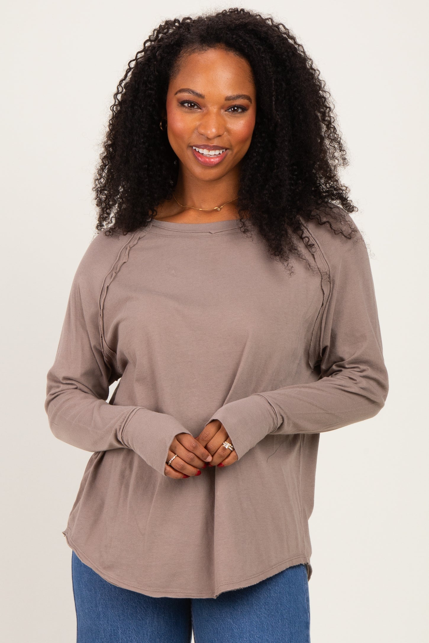 woman wearing a taupe long sleeve top with a relaxed fit and braided detail on the shoulders