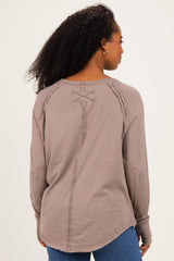 woman wearing a light brown long sleeve top with a unique back detail and relaxed fit