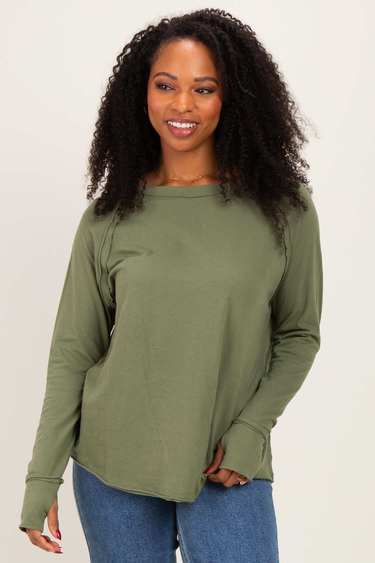 woman wearing an olive green long sleeve top with a relaxed fit and scoop neckline, paired with blue jeans
