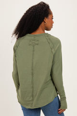 woman wearing a green long sleeve top with unique seam detailing and a relaxed fit, viewed from the back