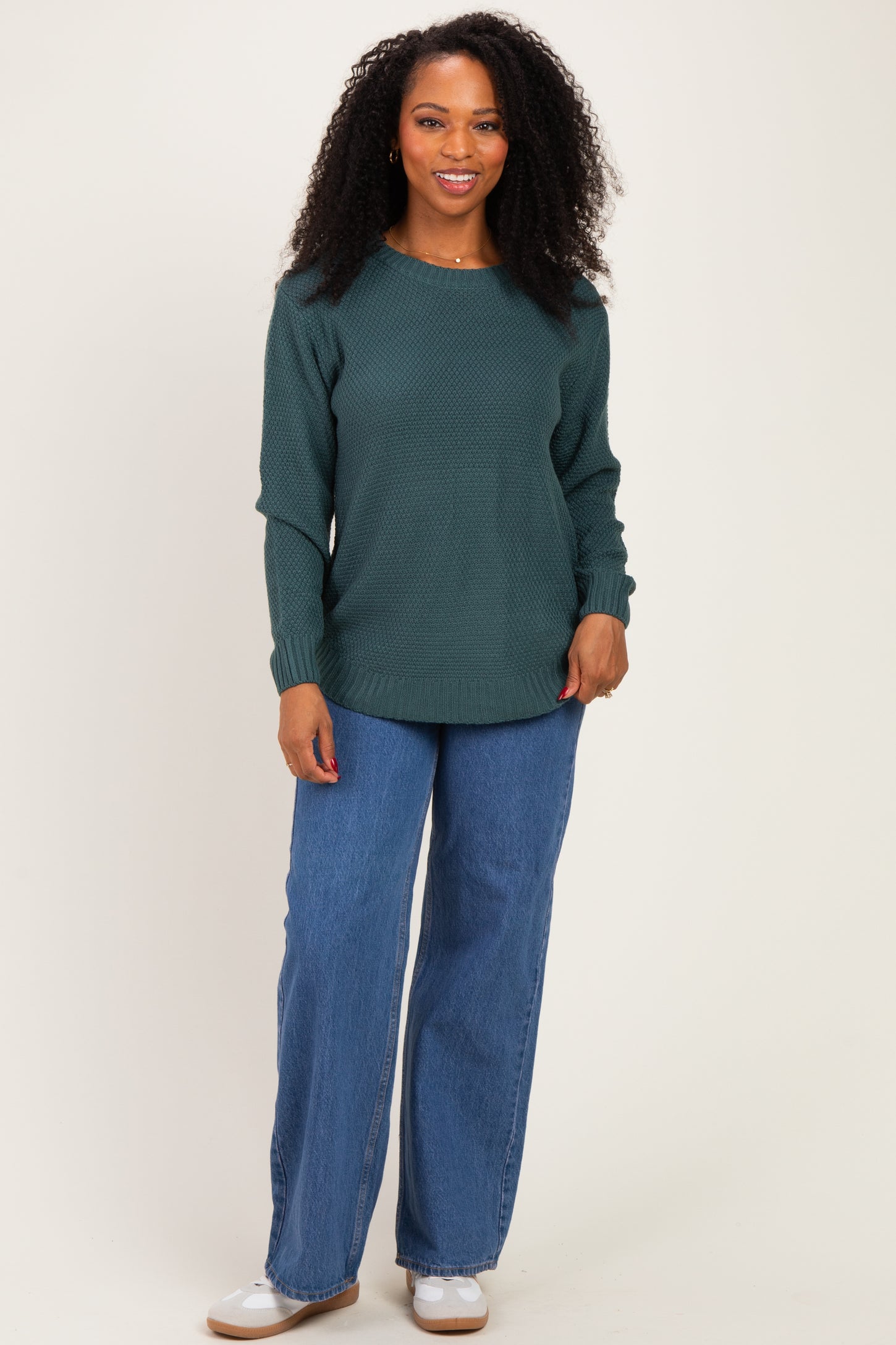 woman wearing a dark green textured long sleeve sweater and wide leg denim jeans