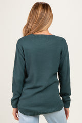 woman wearing a dark teal maternity sweater with a textured knit and relaxed fit, seen from the back