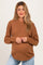 woman wearing a brown knit maternity sweater with a relaxed fit and round neckline, showing her baby bump