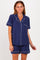 woman wearing a navy blue short sleeve pajama set with white piping details and a front pocket