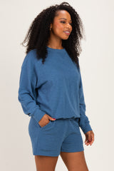 woman wearing a blue long sleeve sweatshirt and matching shorts with pockets