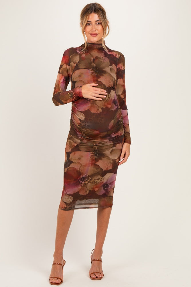 woman wearing a floral print long sleeve maternity dress with ruching and holding her baby bump