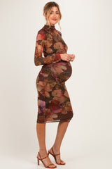 woman wearing a brown floral print maternity dress with ruching, showcasing her baby bump