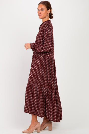 woman wearing a long maroon patterned maxi dress with long sleeves and a tiered hem, styled with beige heels