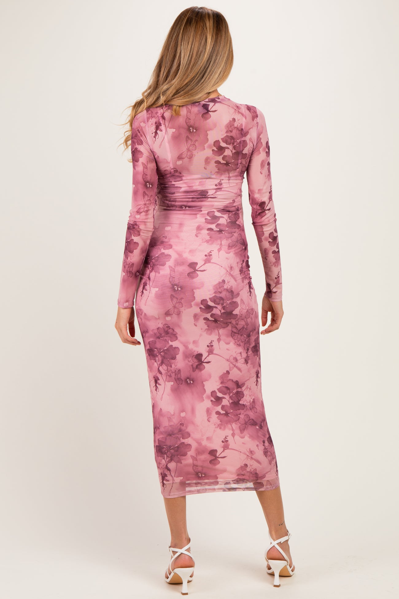 woman wearing a pink floral maternity dress with long sleeves and a fitted silhouette, showcasing a baby bump