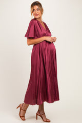 woman wearing a burgundy pleated maternity dress with short sleeves and a visible baby bump