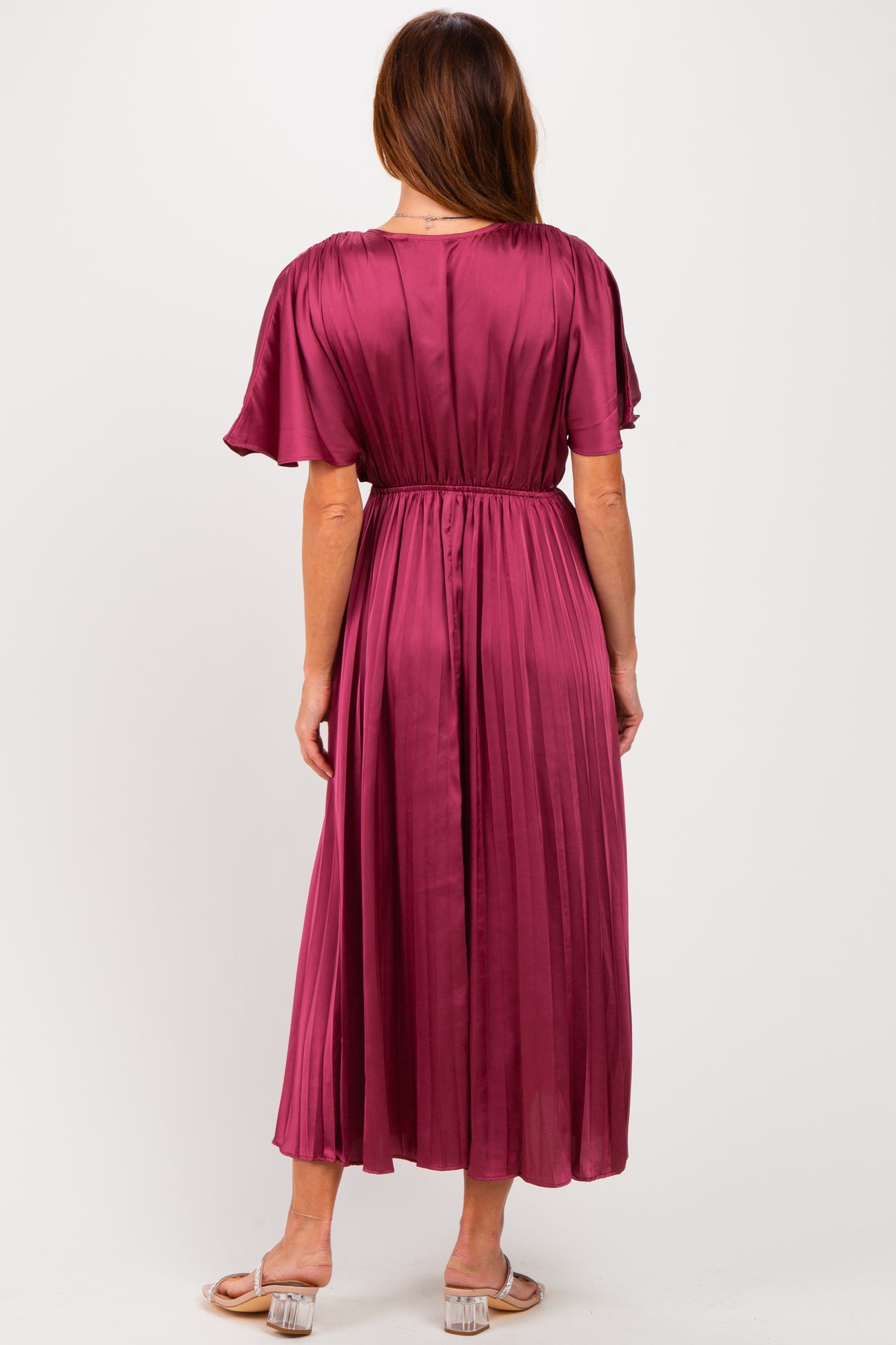 woman wearing a burgundy pleated midi dress with flutter sleeves, viewed from the back