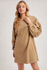 woman wearing a camel-colored long sleeve sweatshirt dress with side pockets and a relaxed fit