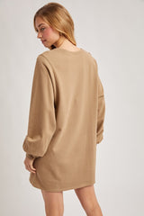 woman wearing a beige long sleeve oversized sweatshirt dress, shown from the back