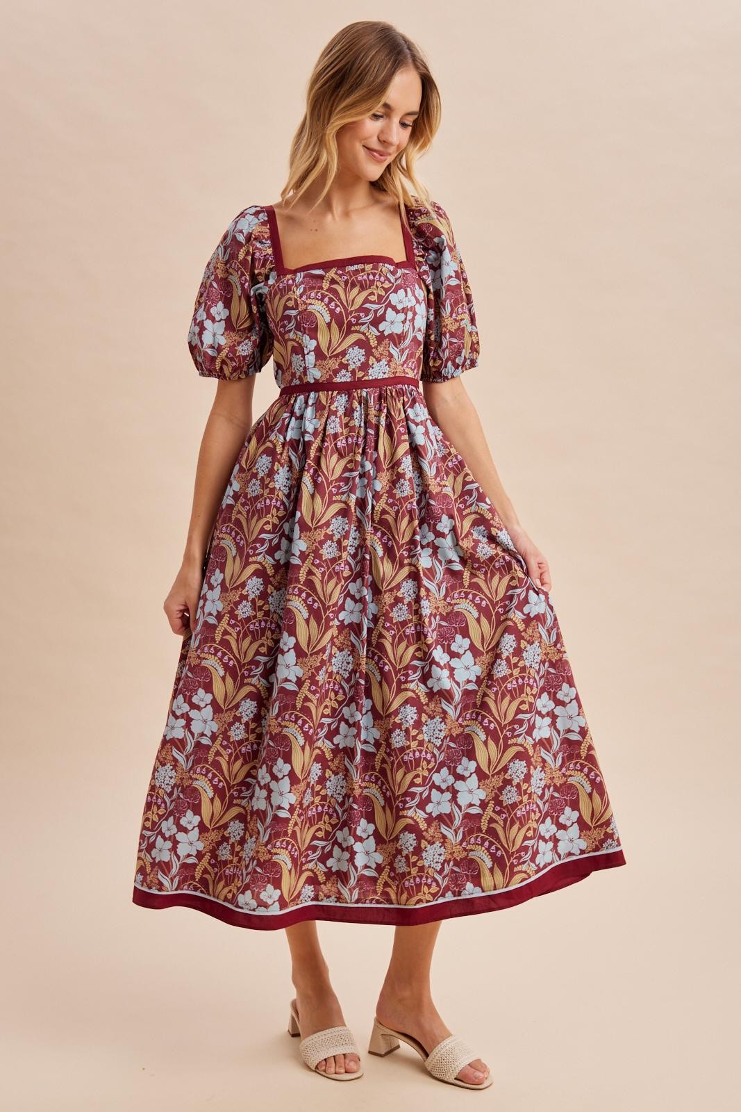 woman wearing a burgundy floral maxi dress with puff sleeves and a square neckline