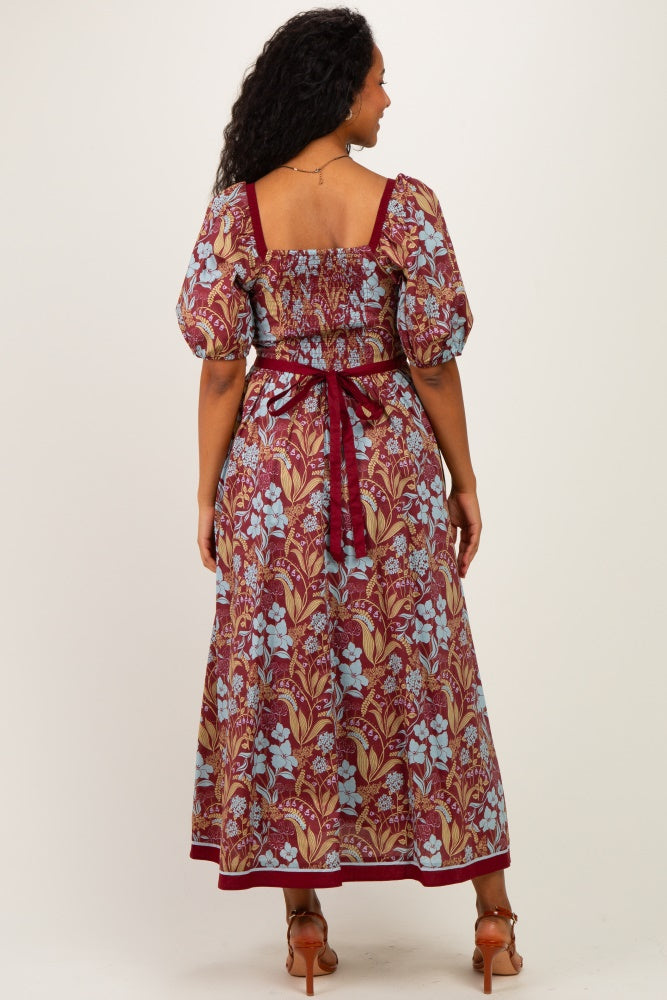 woman wearing a floral print maternity maxi dress with puff sleeves and a tie waist, showing a baby bump from the back