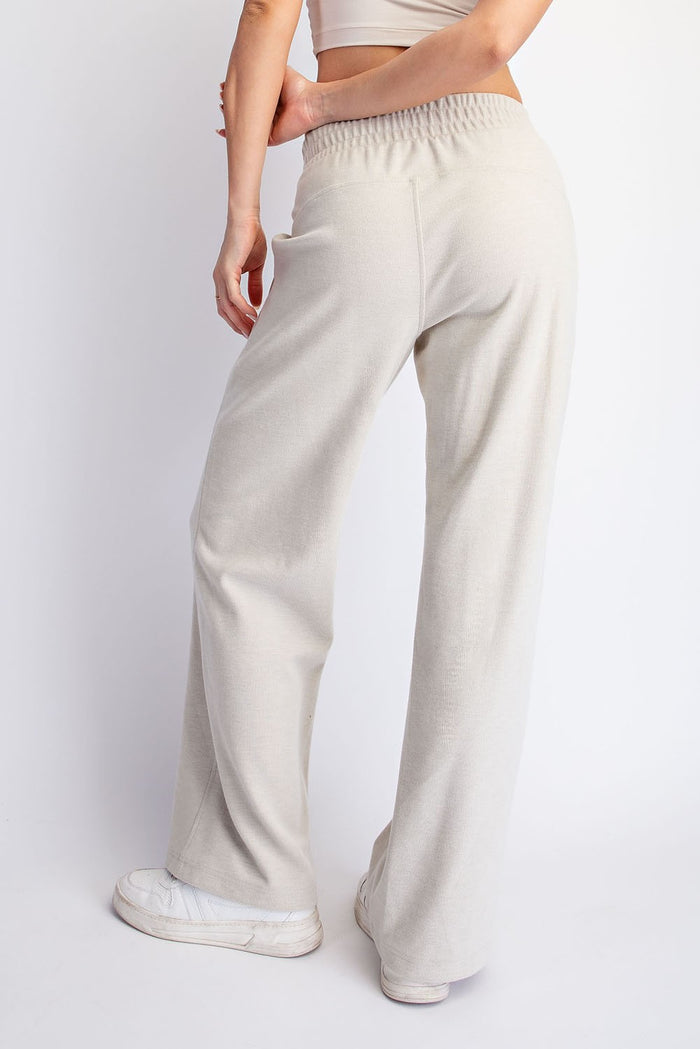 woman wearing light beige wide-leg pants with an elastic waistband, seen from the back