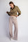 woman wearing a striped brown and olive green cropped sweater and beige wide-leg pants, looking down at her outfit
