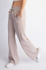 woman wearing beige wide-leg lounge pants with pockets and a drawstring waist
