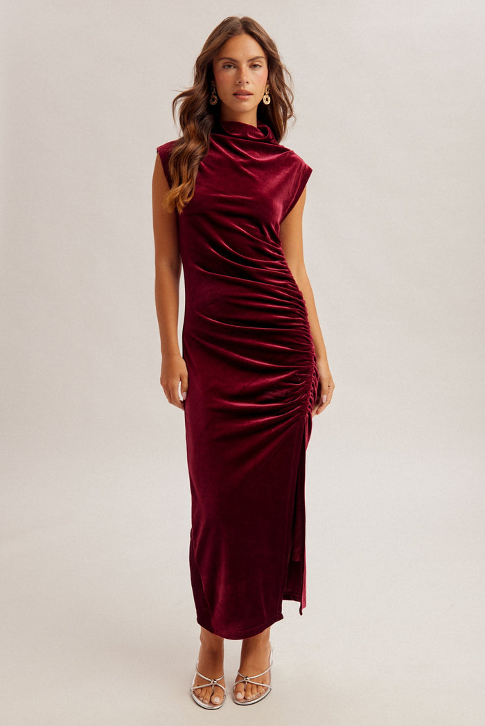 woman wearing a burgundy velvet sleeveless midi dress with side ruching and a high neckline
