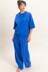 woman wearing a vibrant blue oversized sweatshirt and matching loose-fit pants