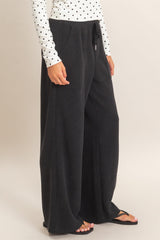 woman wearing black wide-leg lounge pants paired with a white polka dot long sleeve top