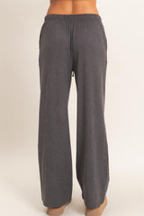 woman wearing dark gray wide-leg sweatpants with an elastic waistband and side pockets, shown from the back