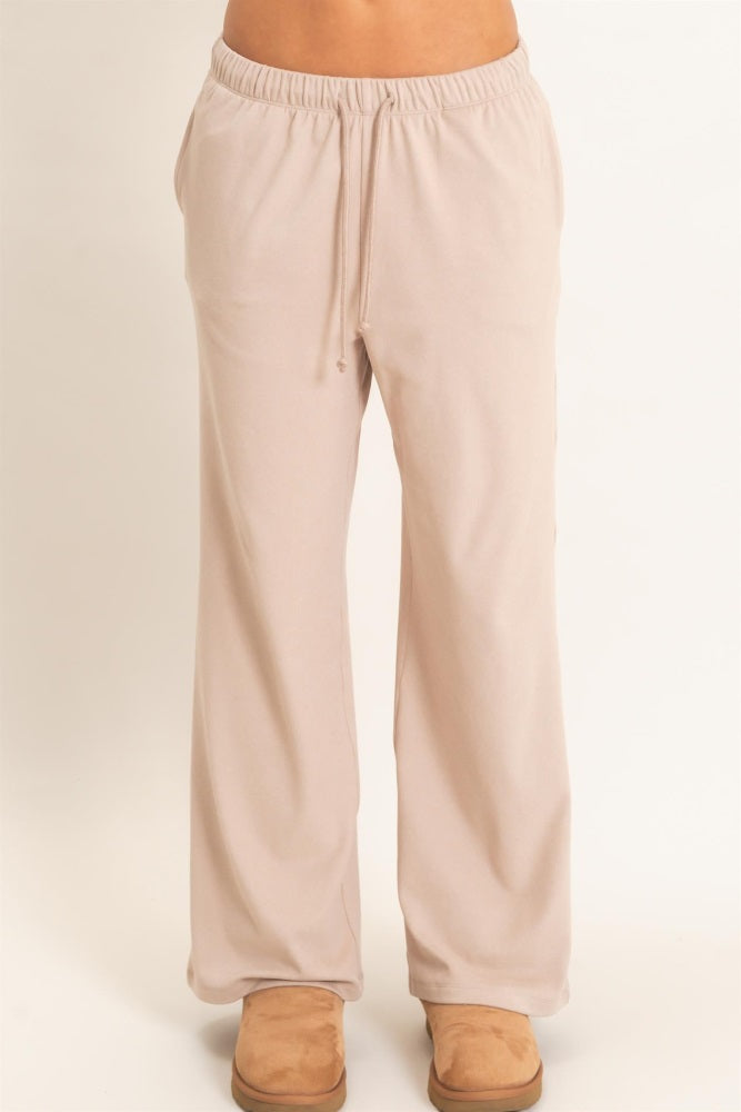 woman wearing light beige relaxed fit lounge pants with an elastic waistband and drawstring