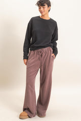 woman wearing a black ribbed sweater and dusty pink wide-leg pants with an elastic waistband and side pockets