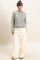 woman wearing a gray and white striped cropped sweater and cream wide-leg pants