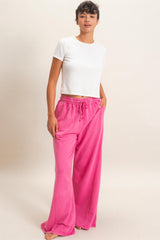 woman wearing a white short sleeve top and pink wide-leg lounge pants with pockets and drawstring waist