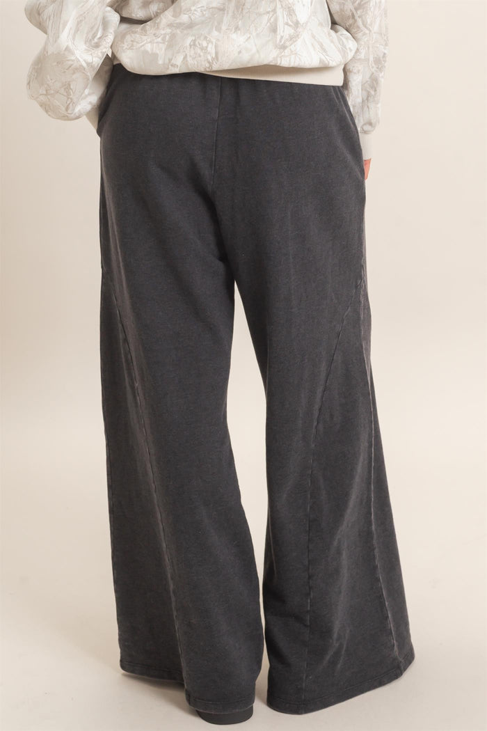 woman wearing dark gray wide-leg pants with side seam details, view from the back