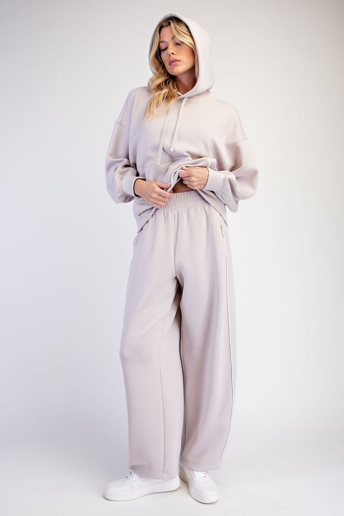 woman wearing a light taupe oversized hoodie and matching wide-leg sweatpants with a relaxed fit