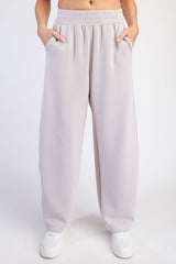 woman wearing light gray wide-leg sweatpants with side pockets and an elastic waistband