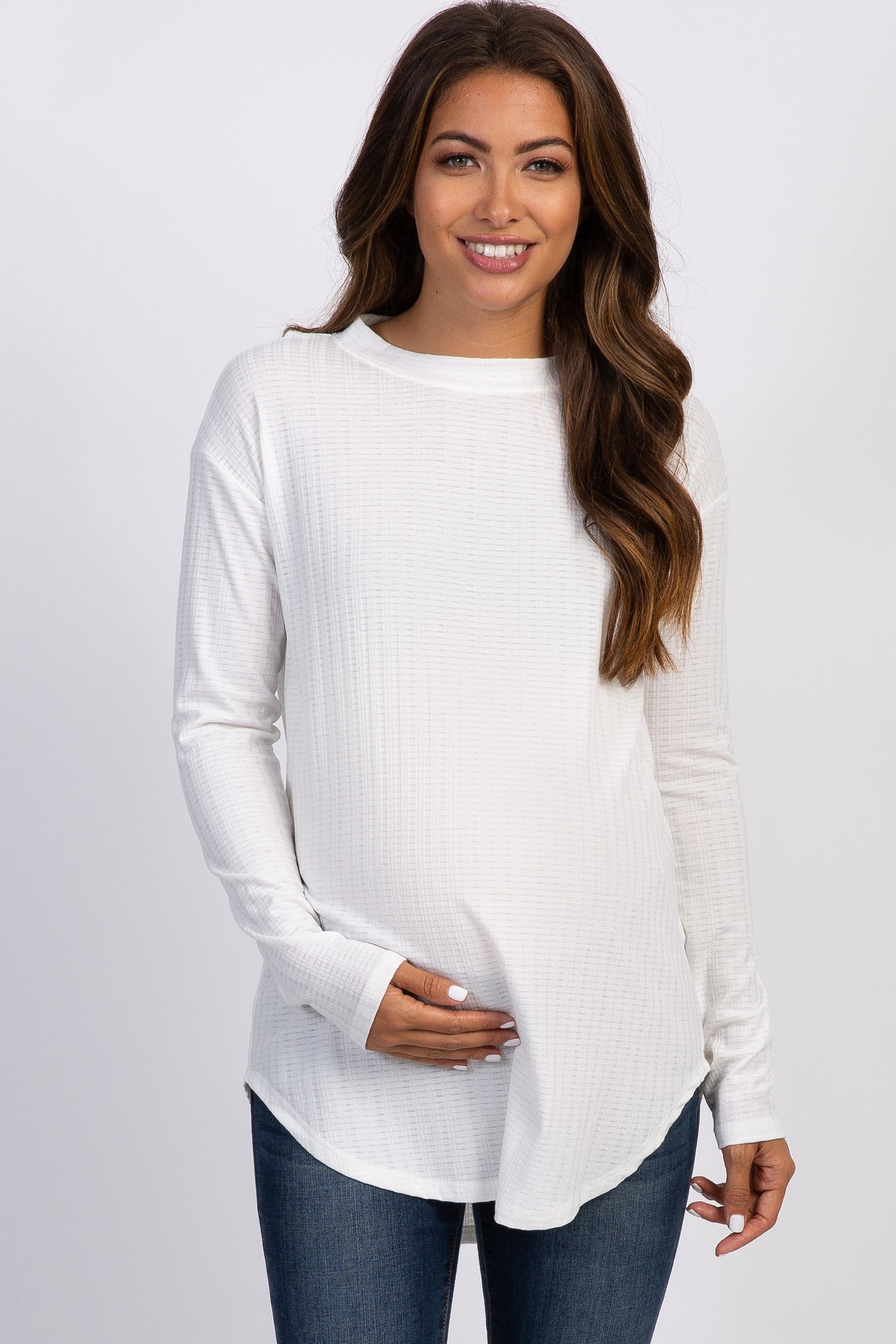 woman wearing a white long sleeve waffle knit tunic top and blue jeans