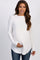 woman wearing a white long sleeve waffle knit tunic top and blue jeans