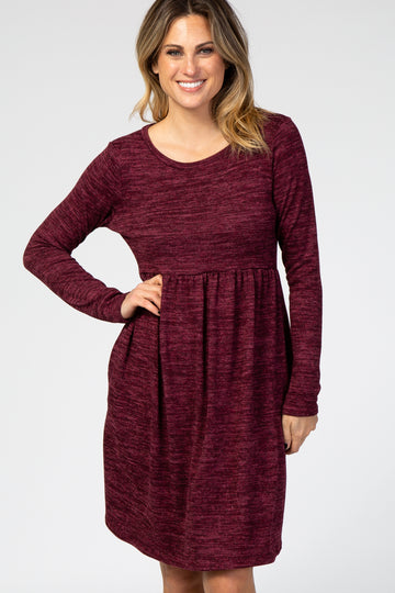 woman wearing a burgundy long sleeve dress with a fitted bodice and a flared skirt