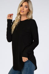 woman wearing a black long sleeve knit top with a relaxed fit and side slits, paired with blue jeans
