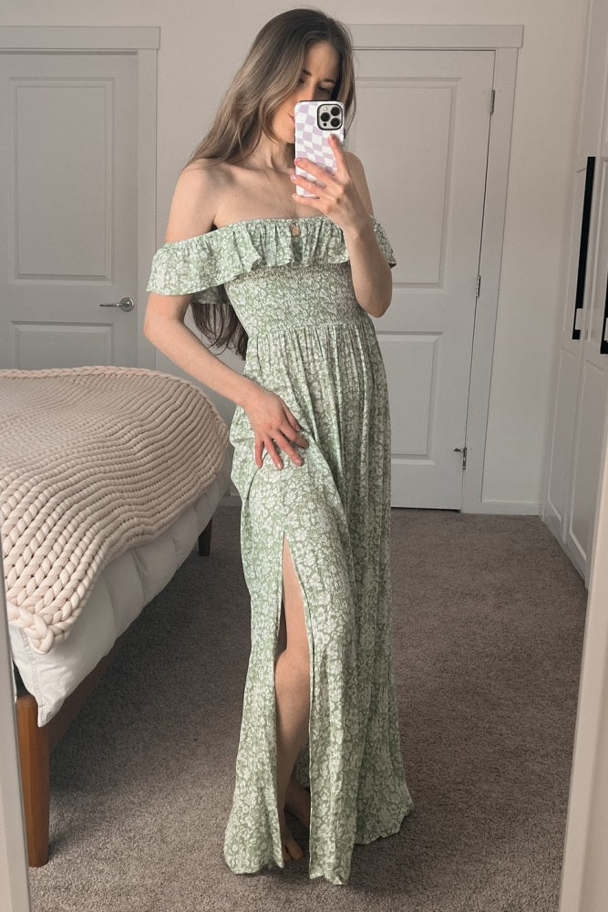 woman wearing a green floral off-the-shoulder maxi dress with a ruched bodice and thigh-high slit