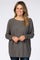 woman wearing a dark gray oversized sweater with a wide neckline and long sleeves, smiling at the camera