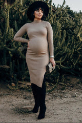 woman wearing a beige ribbed maternity dress with a high neckline and a side slit, holding a handbag, and showing her baby bump