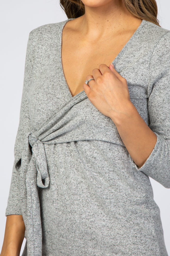 woman wearing a gray long sleeve top with a v-neck and tie detail at the waist