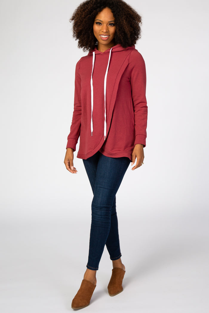 woman wearing a burgundy hooded sweatshirt with a draped front and paired with dark skinny jeans and brown ankle boots