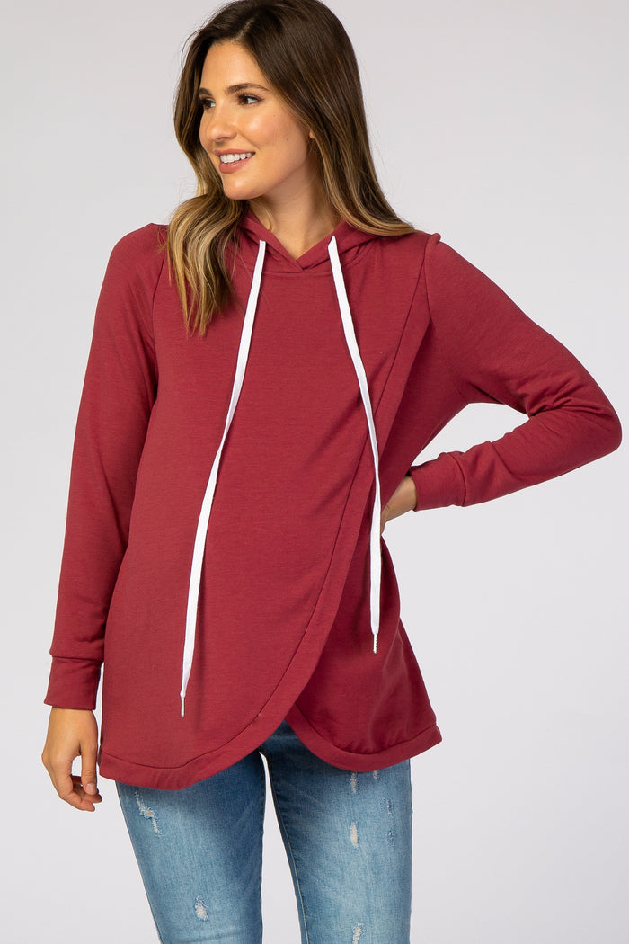 woman wearing a burgundy maternity hoodie with a crossover design and white drawstrings, styled with jeans