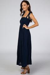 woman wearing a navy blue maxi dress with smocked bodice and tie straps, posing sideways