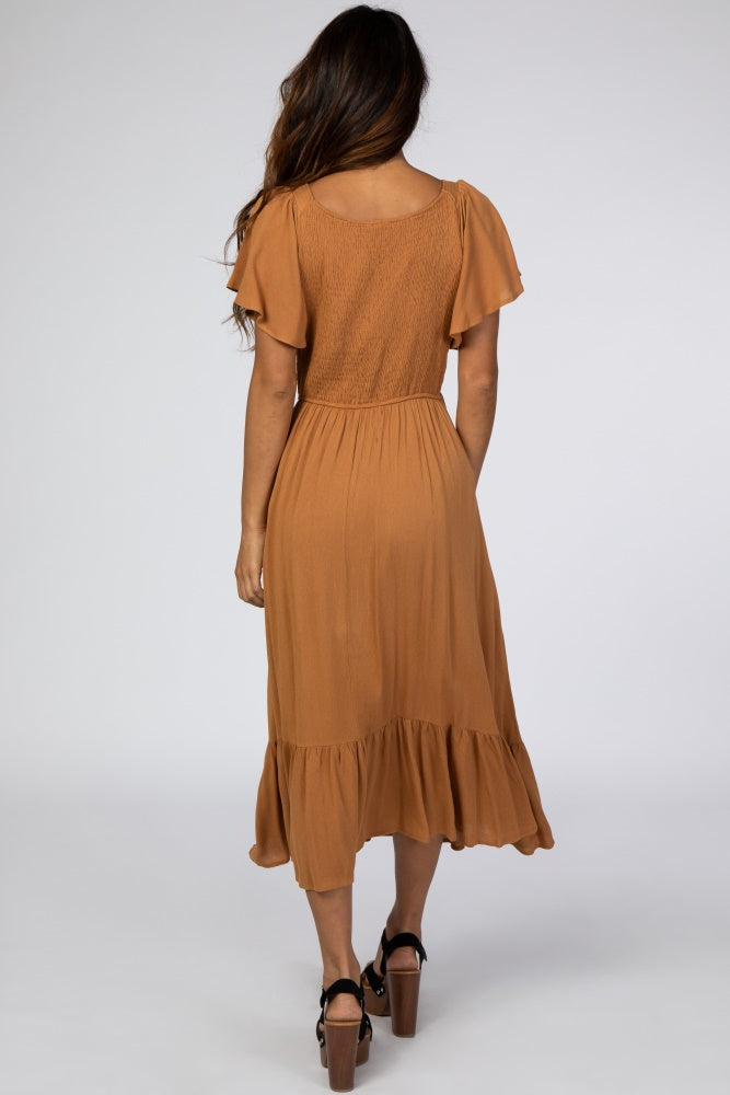 woman wearing a rust-colored midi dress with flutter sleeves and a ruffled hem, viewed from the back