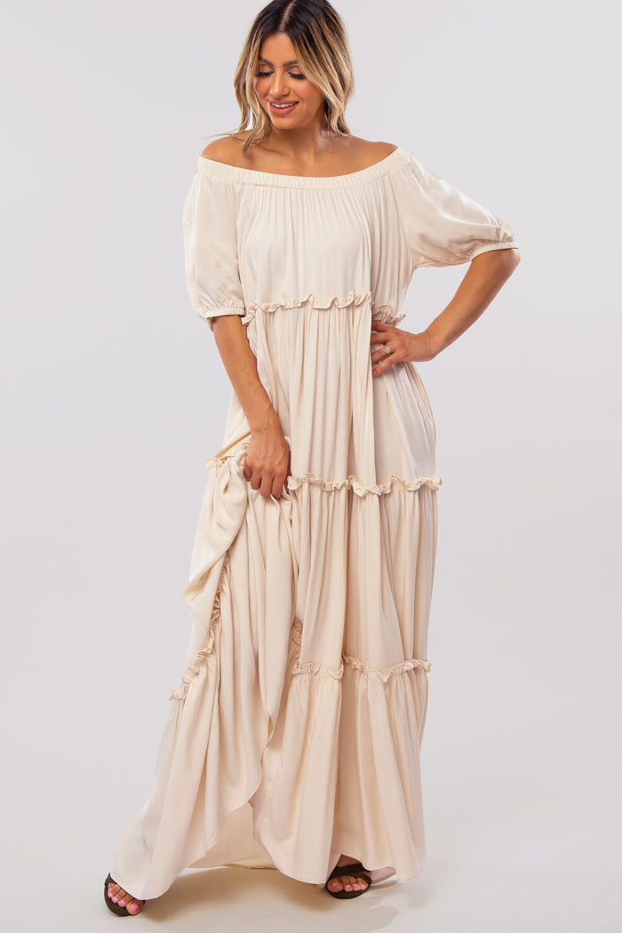 woman wearing a beige off-the-shoulder maxi dress with ruffles and short sleeves