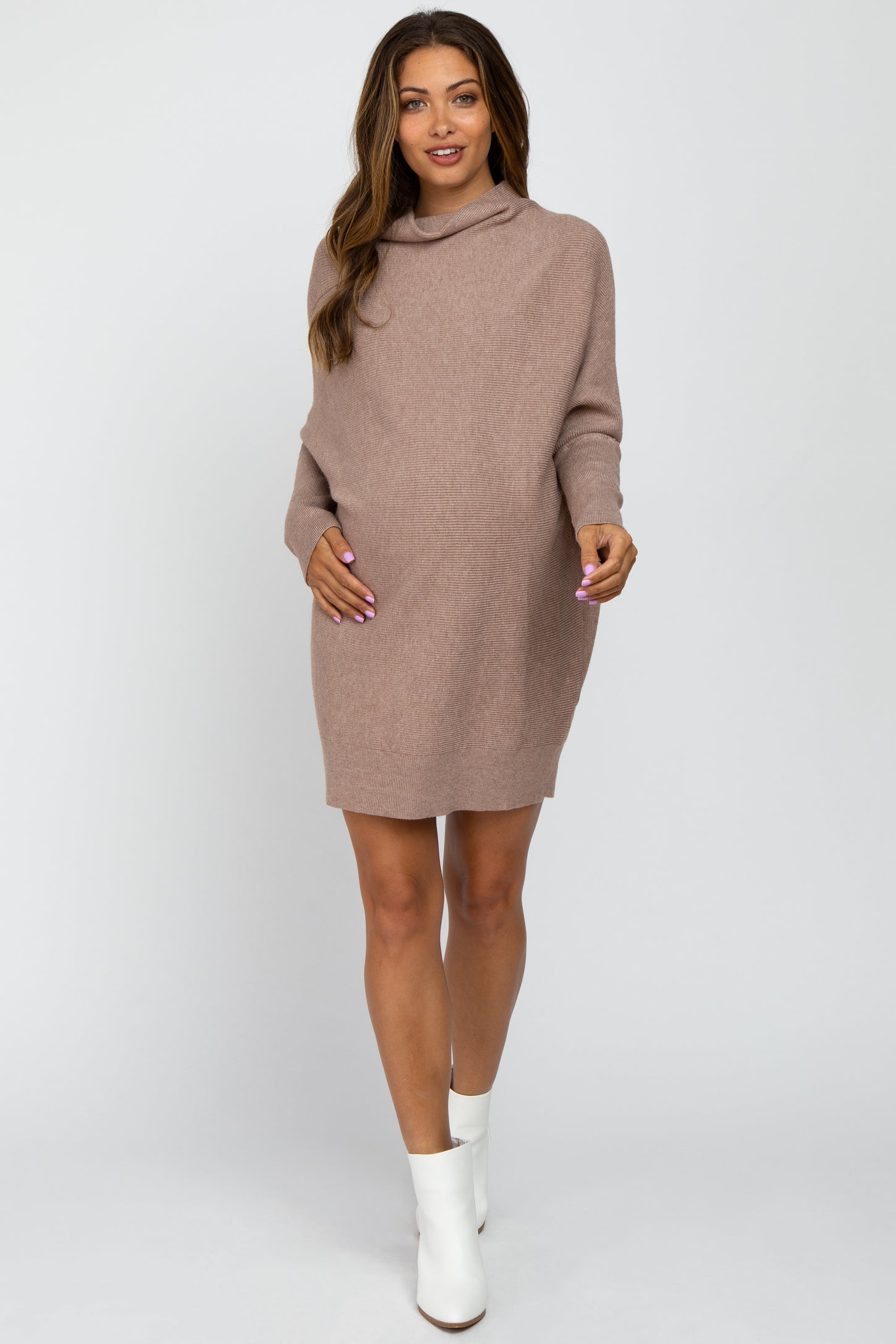 woman wearing a taupe oversized maternity sweater dress and holding her baby bump