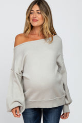 woman wearing a light gray off-shoulder maternity sweater with balloon sleeves and a visible baby bump