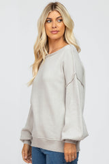 woman wearing a light gray oversized sweater with balloon sleeves and a relaxed fit